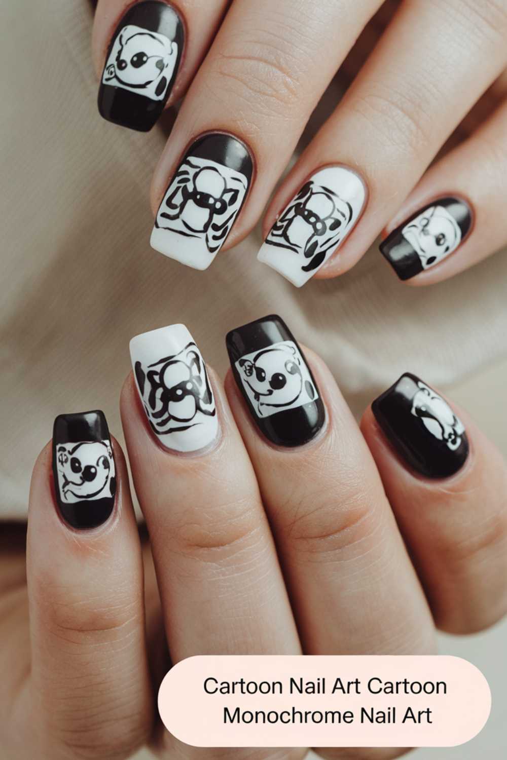 Close-up of hands showcasing monochrome cartoon nail art designs. Each nail features unique black and white illustrations, creating a playful and stylish look.