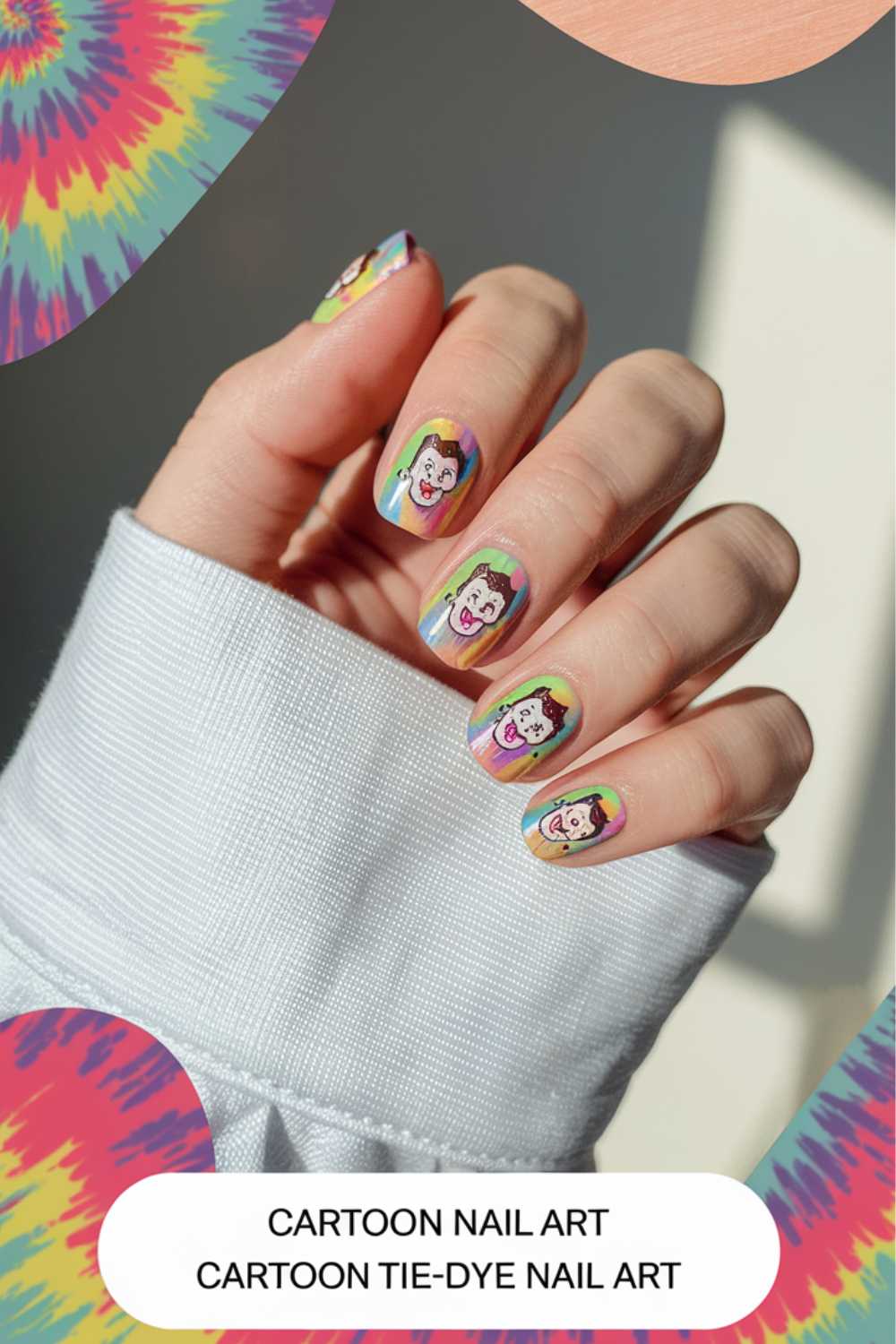 Hand with cartoon-themed nail art designs featuring colorful illustrations on each fingernail. The background bursts with vibrant tie-dye patterns. Text at the bottom reads Cartoon Nail Art Designs and Cartoon Tie-Dye Nail Art. A cozy sweater sleeve peeks into view.